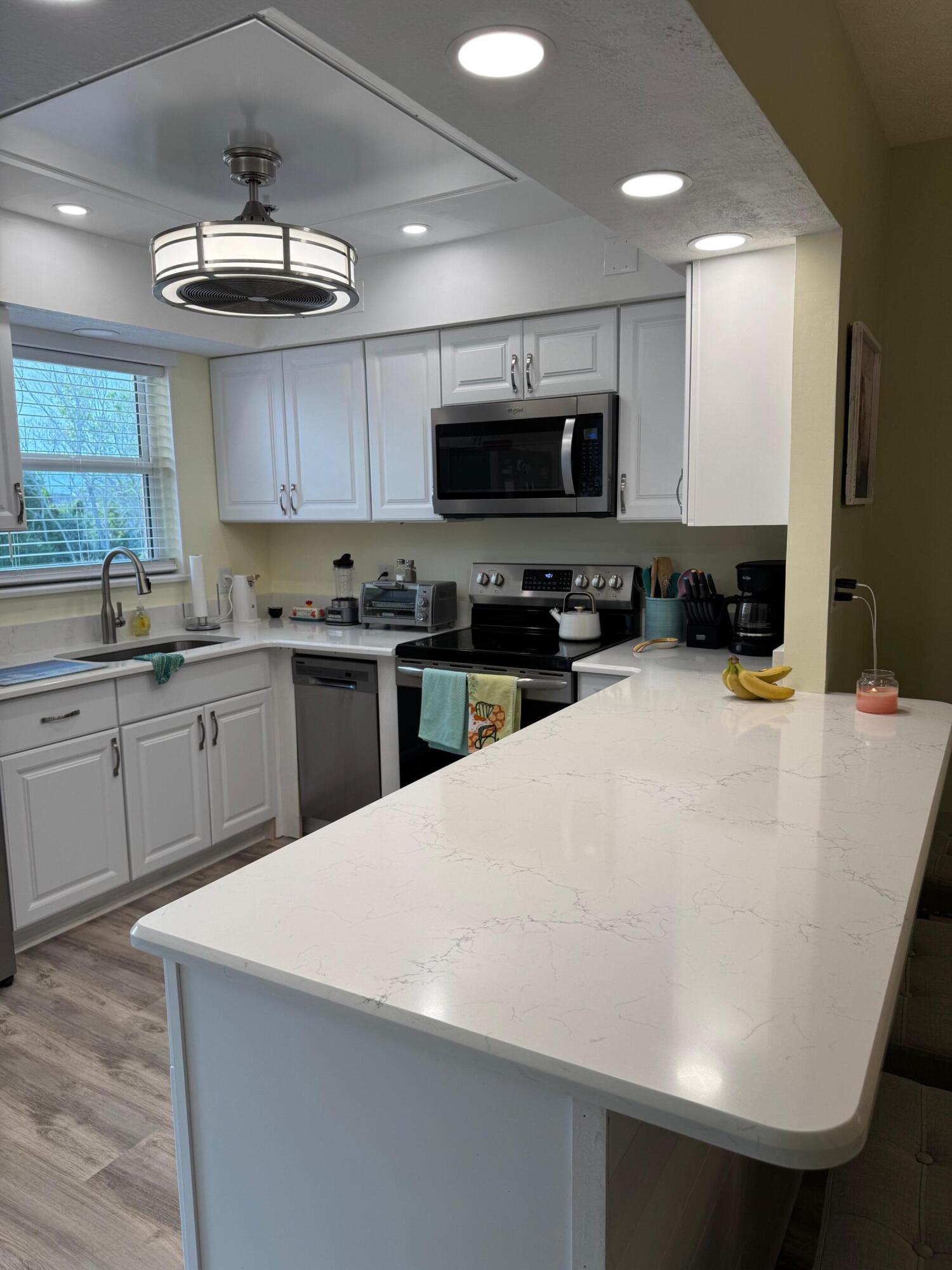 2950 Southeast Ocean Boulevard, Unit 110202 Stuart, FL 34996 - Photo 5 of 25 a kitchen with a sink a microwave and cabinets