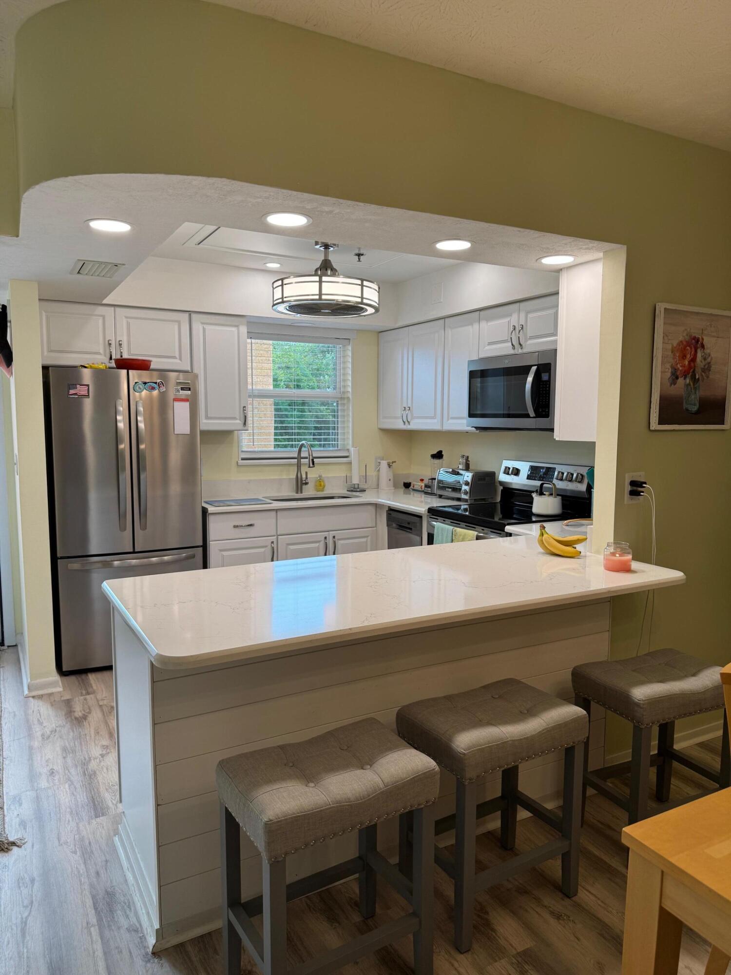 2950 Southeast Ocean Boulevard, Unit 110202 Stuart, FL 34996 - Photo 6 of 25 a kitchen with stainless steel appliances a dining table chairs refrigerator and microwave