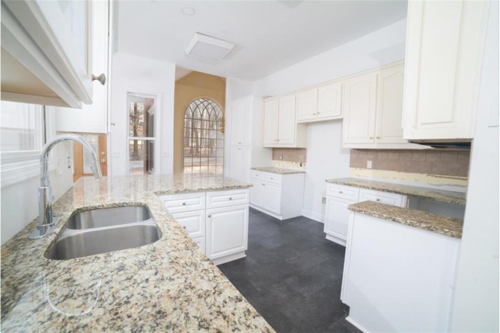 2210 Cammie Wages Road Dacula, GA 30019 - Photo 16 of 32 a kitchen with granite countertop a sink a stove and cabinets