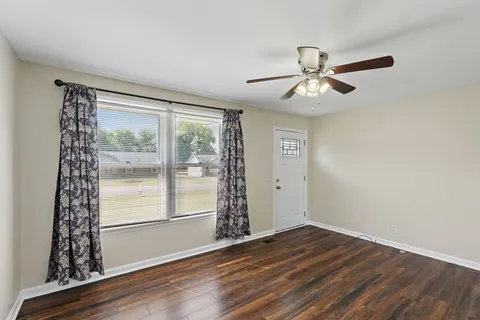 a view of an empty room with window and wooden floor