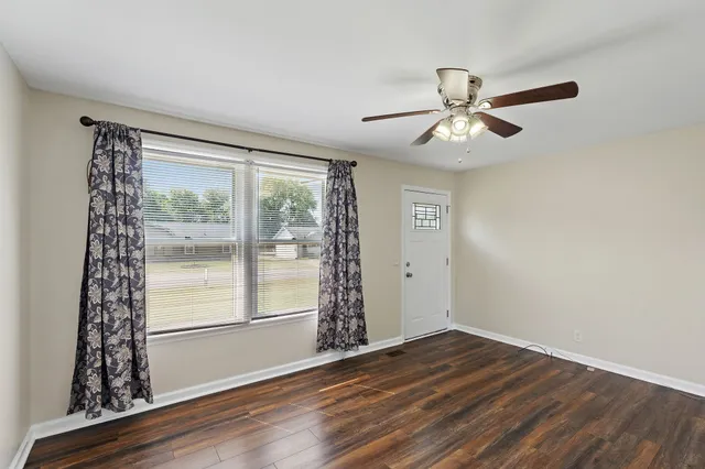 a view of an empty room with window and wooden floor