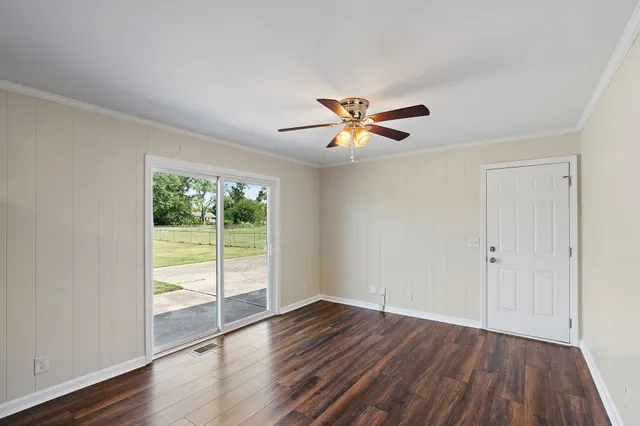 a view of an empty room with a window and wooden floor