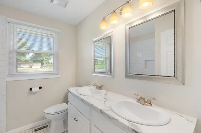 a bathroom with a toilet a sink a mirror and a window