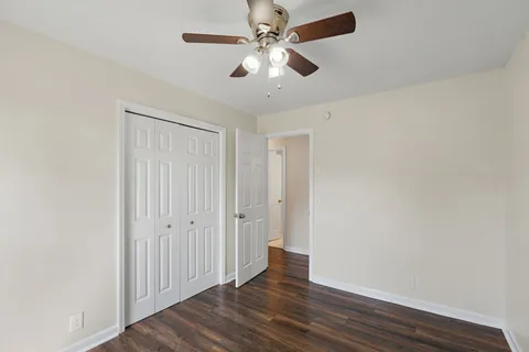 an empty room with wooden floor fan and windows