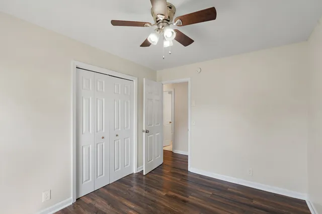 an empty room with wooden floor fan and windows