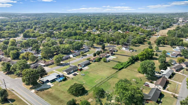 an aerial view of residential houses with outdoor space and trees