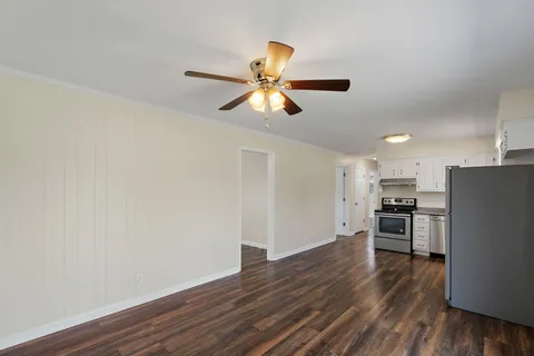 a view of kitchen with wooden floor a ceiling fan and stainless steel appliances