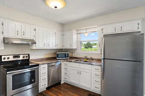 a kitchen with white cabinets stainless steel appliances and a window