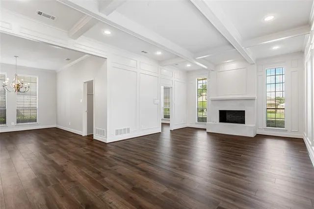 an empty room with wooden floor fireplace and windows
