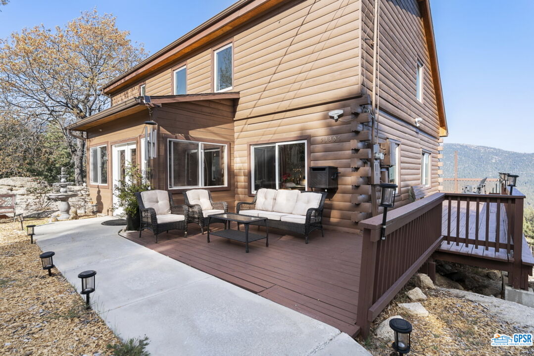 53305 Big Rock Drive Idyllwild, CA 92549 - Photo 18 of 67 a view of a patio with couches table and chairs with wooden floor and fence