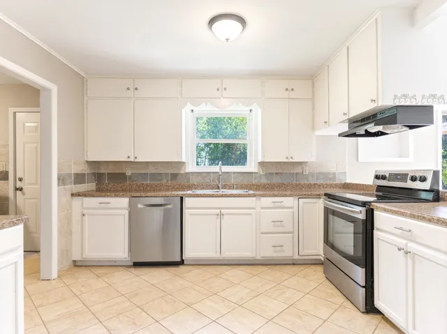 a kitchen with granite countertop white cabinets white appliances with a sink and dishwasher