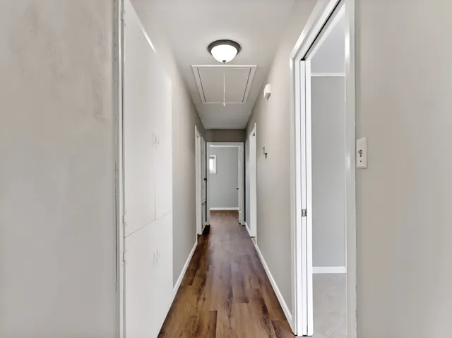 a view of a hallway with a door and wooden floor