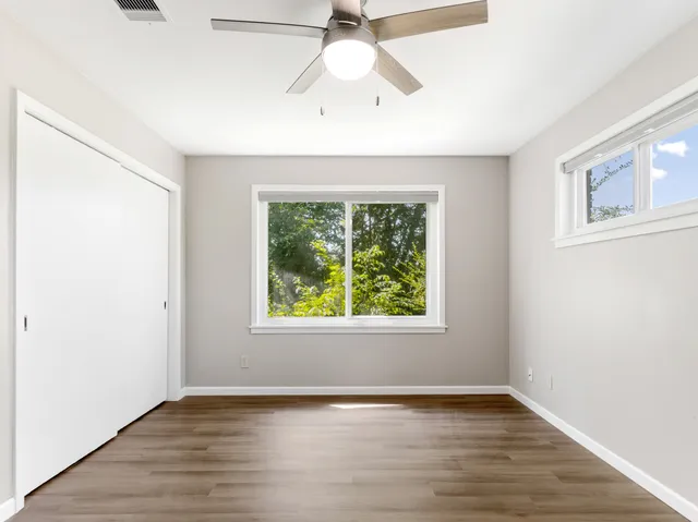 an empty room with wooden floor and windows