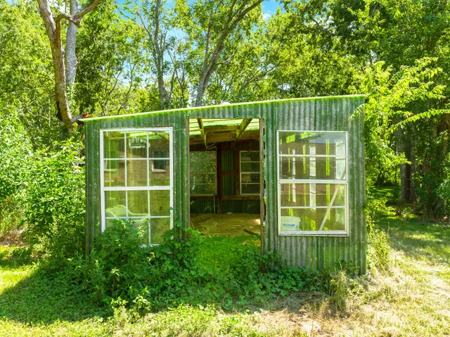 a view of a house with a small yard and large trees