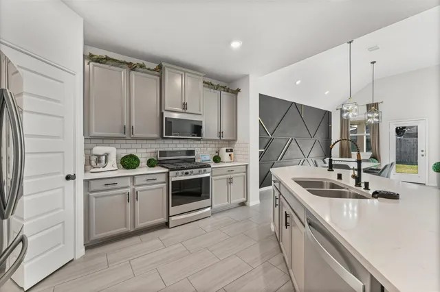 a kitchen with granite countertop a sink stainless steel appliances and cabinets