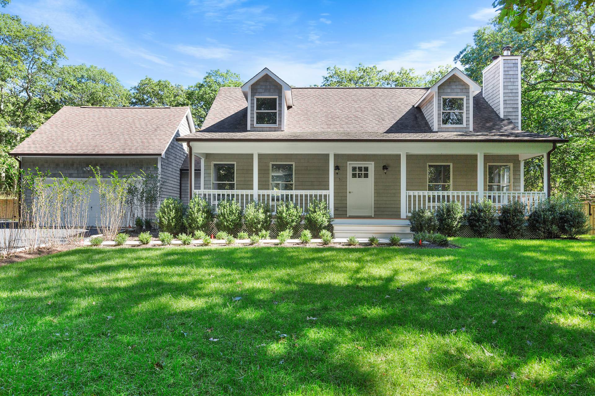 a front view of a house with a yard and potted plants