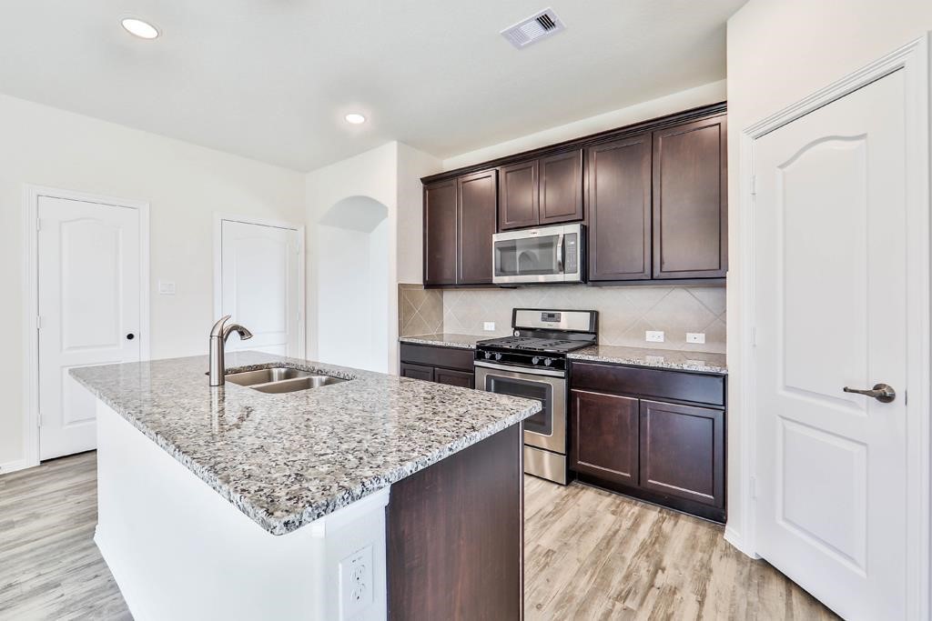 247 Sintra Lk Way Rosenberg, TX 77469 - Photo 7 of 28 a kitchen with stainless steel appliances granite countertop a sink stove and refrigerator
