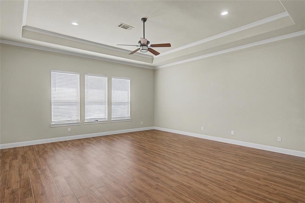 143 Wrigley Drive Springtown, TX 76082 - Photo 21 of 38 Huge Primary Suite with a ceiling fan, wood like finished floors, crown molding, and a tray ceiling