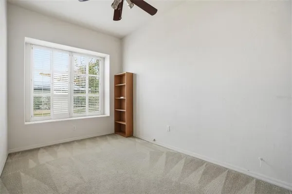 an empty room with windows and fan