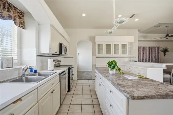 a large white kitchen with granite countertop a sink and white cabinets