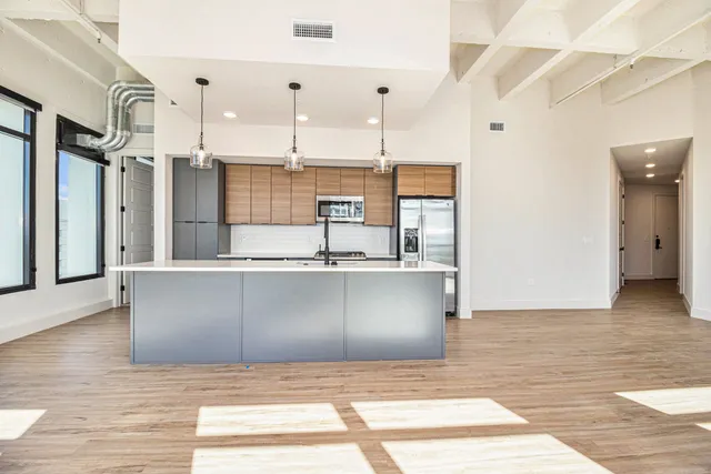 a view of a kitchen with kitchen island a refrigerator wooden floor and a sink