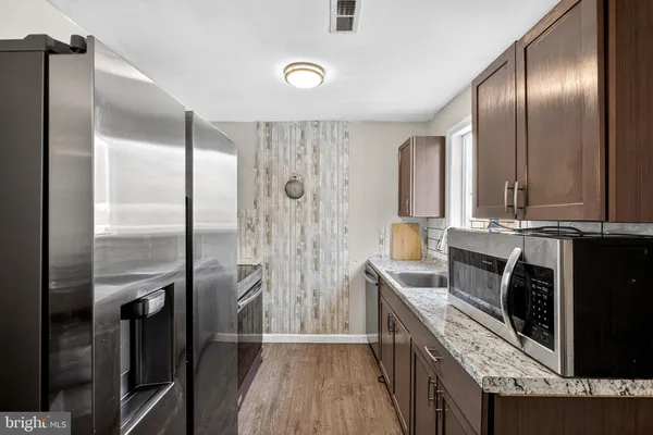 a kitchen with stainless steel appliances granite countertop a refrigerator a stove and a sink with wooden floor