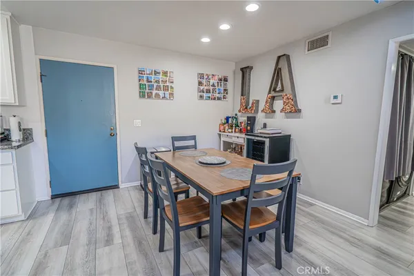 a kitchen with granite countertop a dining table chairs cabinets and stainless steel appliances