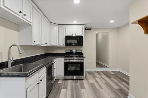 a kitchen with granite countertop a sink stove and refrigerator