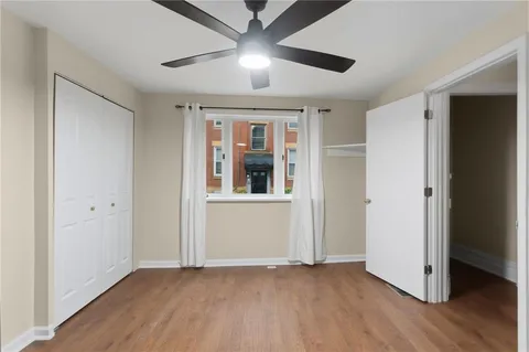 a view of an empty room with wooden floor and a ceiling fan