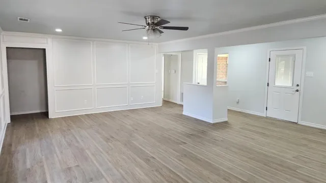 an empty room with wooden floor and windows