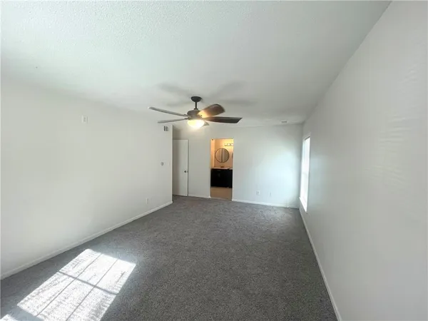 en empty room with windows and fan