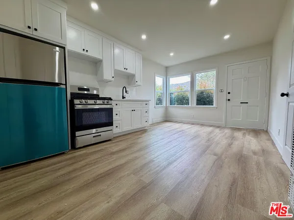 a large kitchen with stainless steel appliances a large counter top a stove and a wooden floors