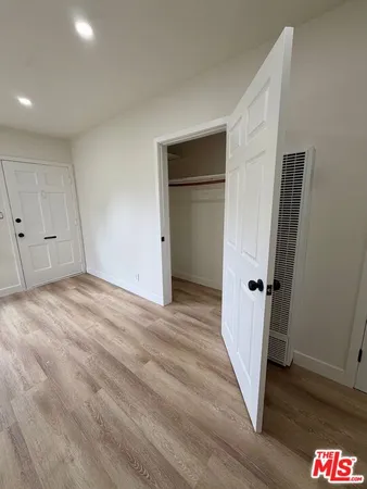 a view of a hallway with wooden floor and closet