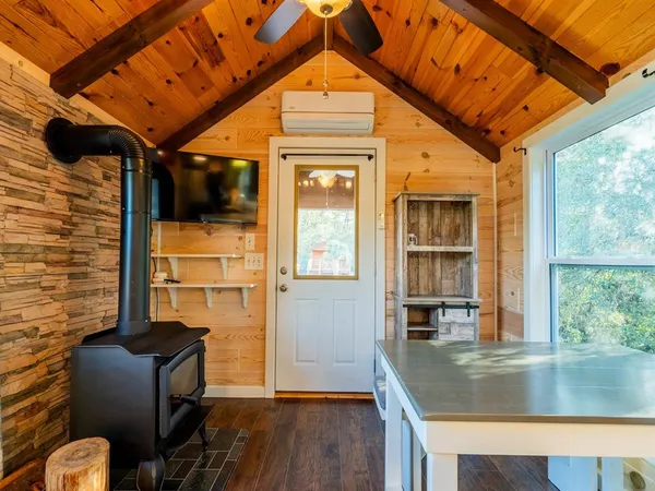 a view of a wooden house with large trees next to a yard
