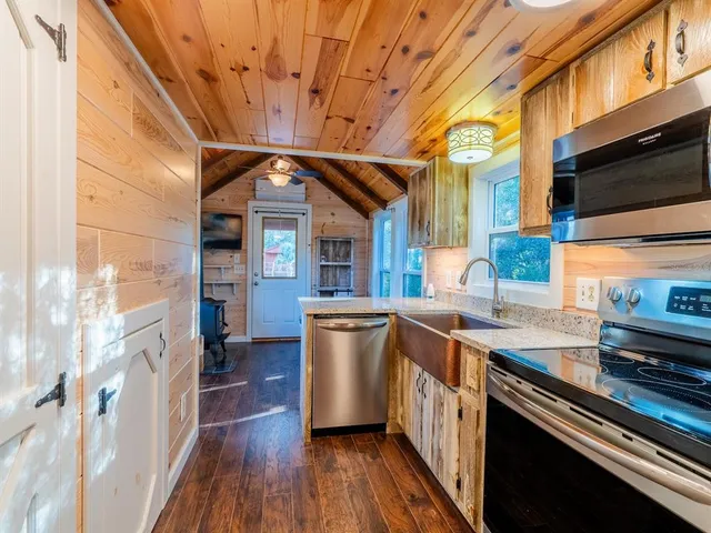 a kitchen with stainless steel appliances granite countertop a stove a refrigerator a dining table and chairs with wooden floor