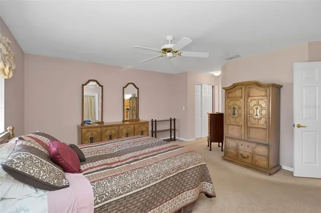 a bedroom with a bed a ceiling fan and a dresser