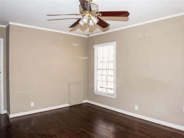 an empty room with wooden floor chandelier fan and windows