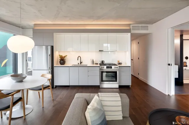 a kitchen with stainless steel appliances a dining table chairs and a refrigerator