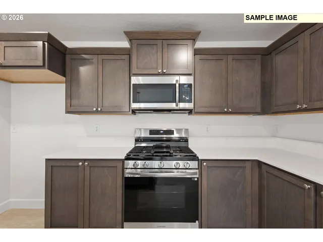 a kitchen with stainless steel appliances a stove a microwave cabinets and a counter top space