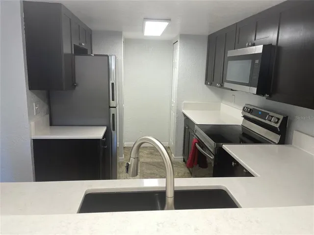 a view of kitchen with stainless steel appliances kitchen island sink refrigerator and stove