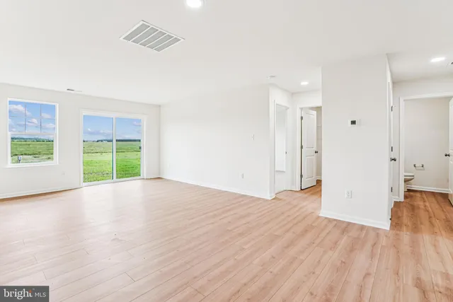 a view of an empty room with wooden floor and window