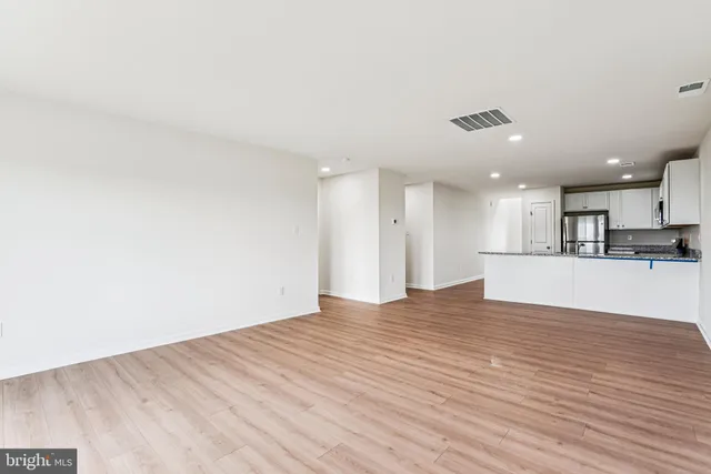a view of kitchen and empty room with wooden floor