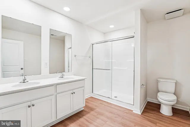 a spacious bathroom with a toilet a sink a mirror and a shower