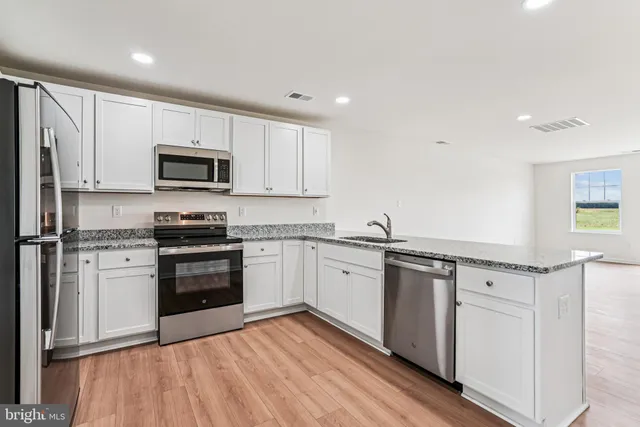 a kitchen with granite countertop white cabinets and stainless steel appliances