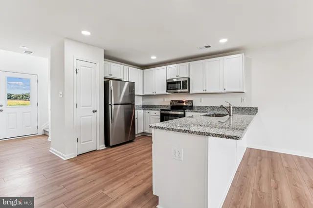 a kitchen with granite countertop a refrigerator and a stove top oven