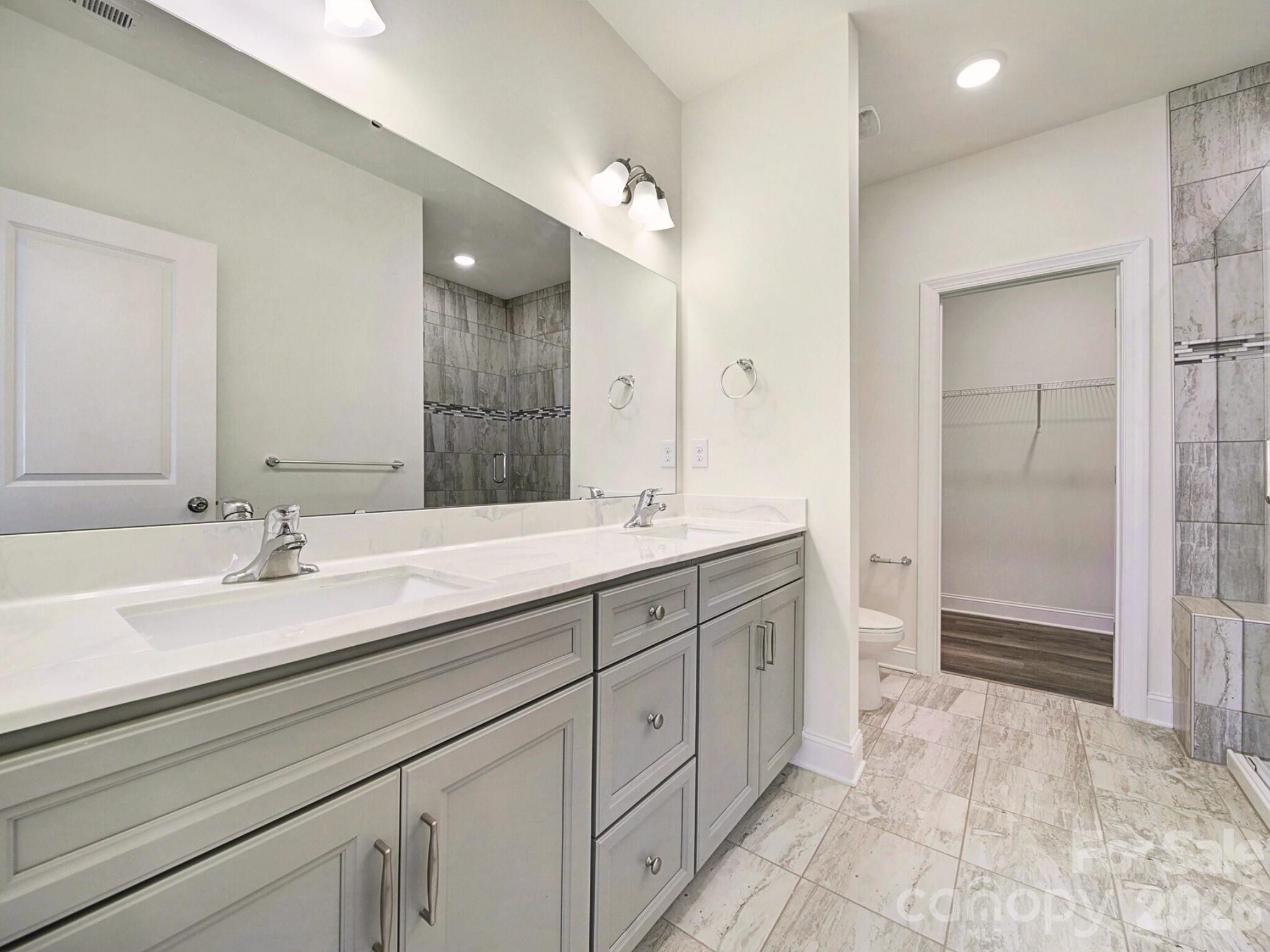 4003 Rothwood Lane Harrisburg, NC 28075 - Photo 13 of 30 a spacious bathroom with a granite countertop sink a toilet a mirror and shower