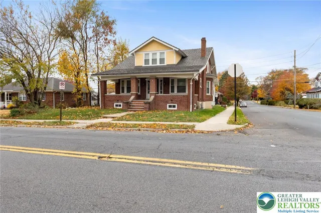 a front view of residential houses with yard and trees