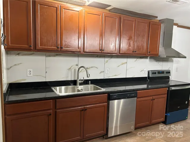a kitchen with stainless steel appliances granite countertop a sink dishwasher stove and cabinets with wooden floor