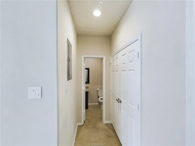 a view of a hallway with closet and a bathroom