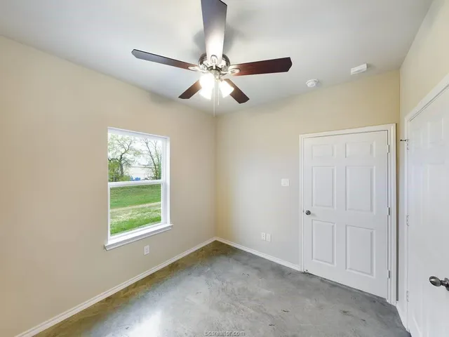 an empty room with windows and fan